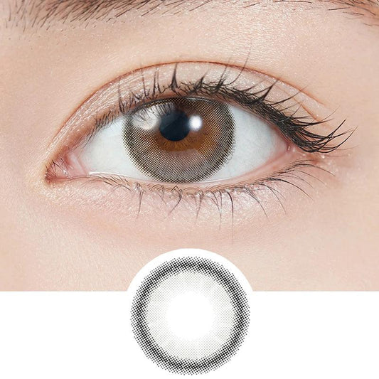 Close-up shot of model's eye adorned with Topards 1-Day Grege Quartz (10pk) daily color contact lenses with prescription, paired with clean-girl eye makeup, showing the brightening and enlarging effect of the circle contact lens on dark brown eyes, above a cutout of the contact lens with limbal ring on a white background.